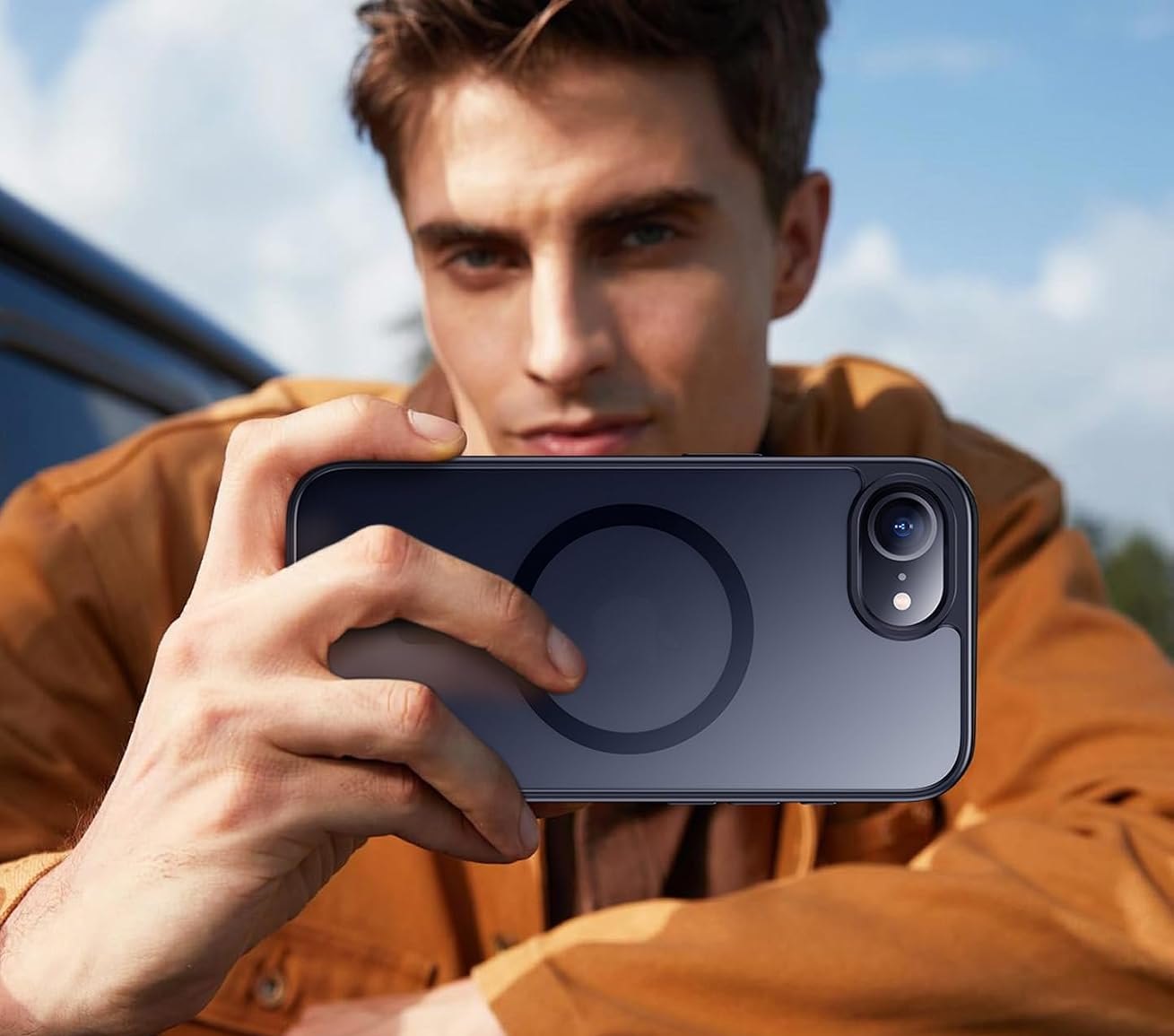 A man framing a photo with an iPhone in a black SPIDERCASE magnetic matte case